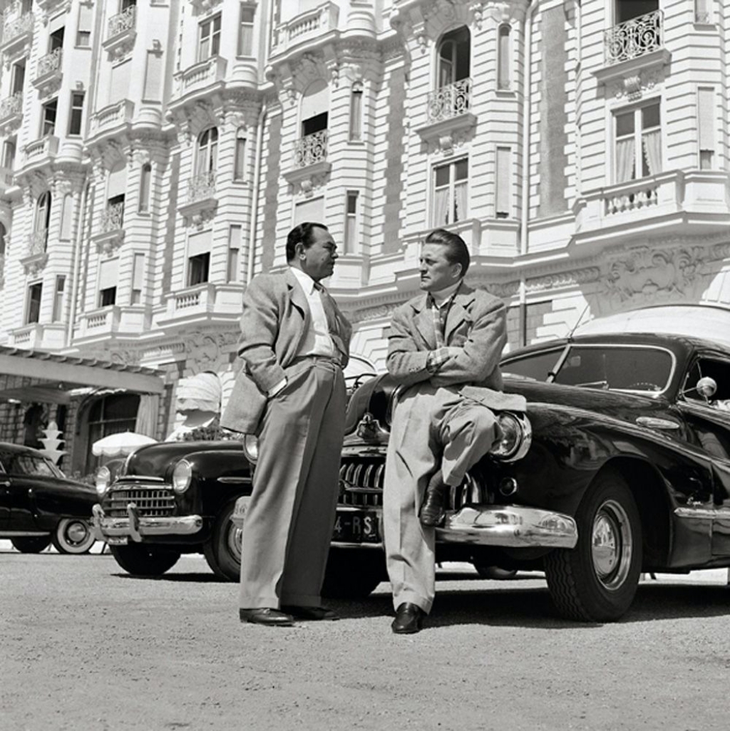 Kirk Douglas y Edward G. Robinson delante de un Buick en Cannes en 1948 | Edward Quinn